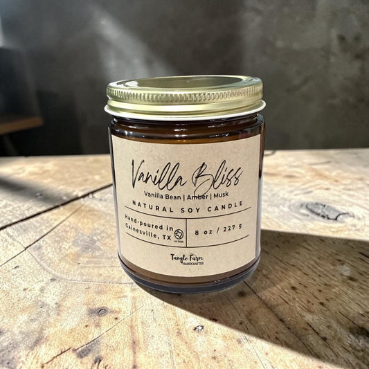 Vanilla Bliss candle jar on a wooden surface with a blurred background