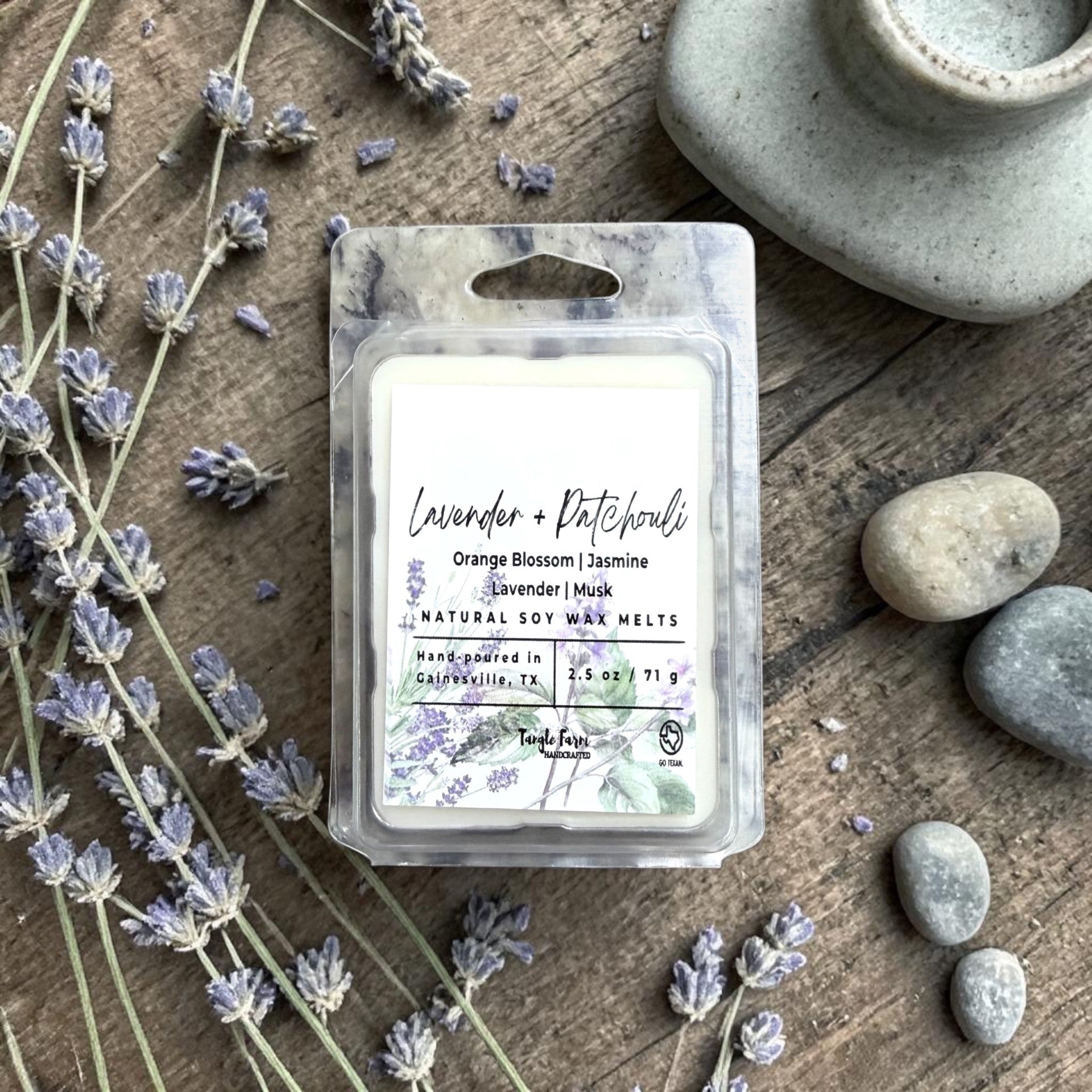 Packaged lavender wax melts on a wooden surface with lavender flowers and stones.