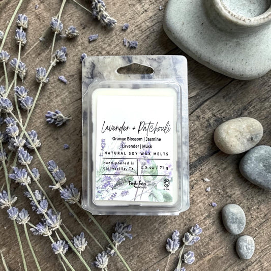 Packaged lavender wax melts on a wooden surface with lavender flowers and stones.