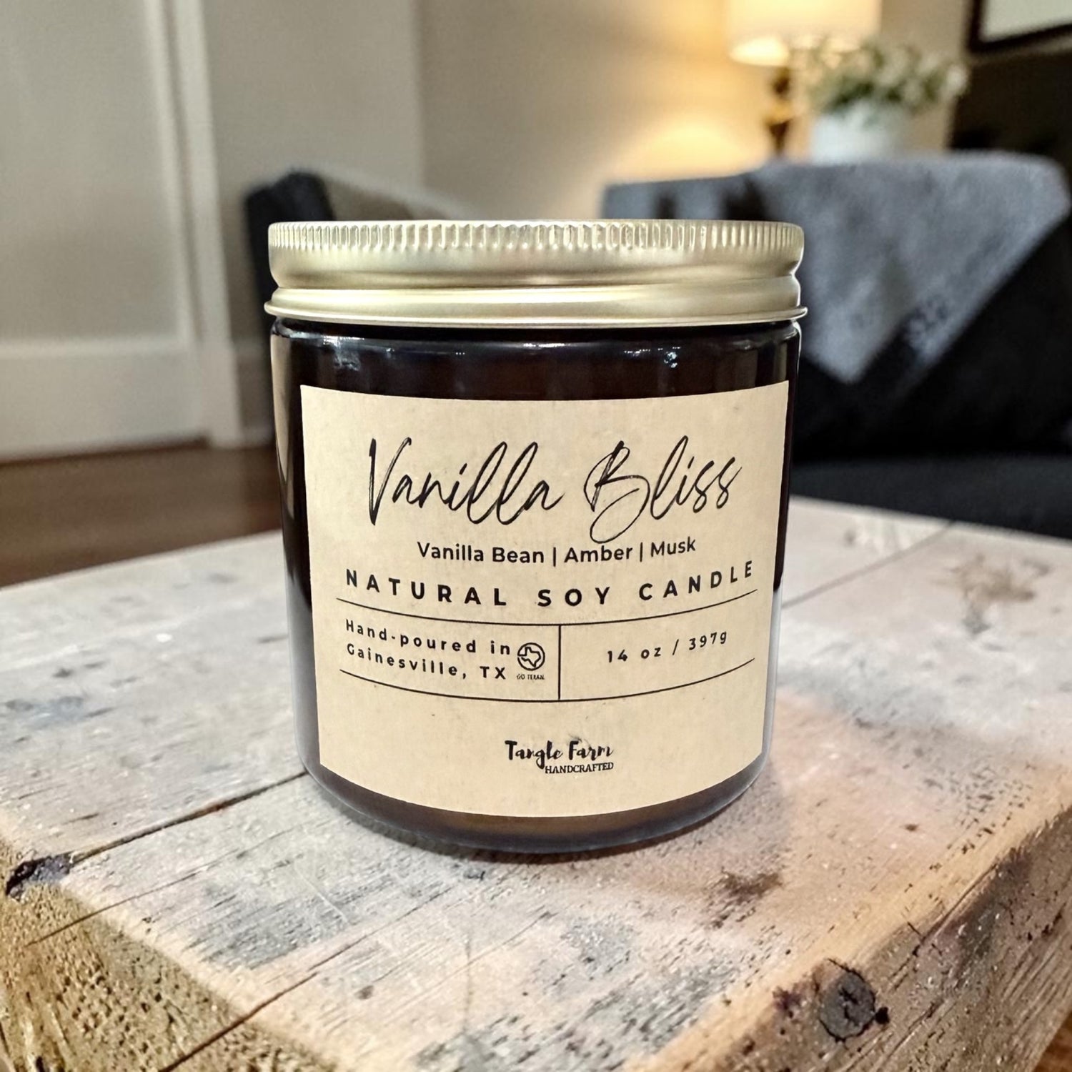 Vanilla Bliss natural soy candle on a wooden surface with a blurred indoor background